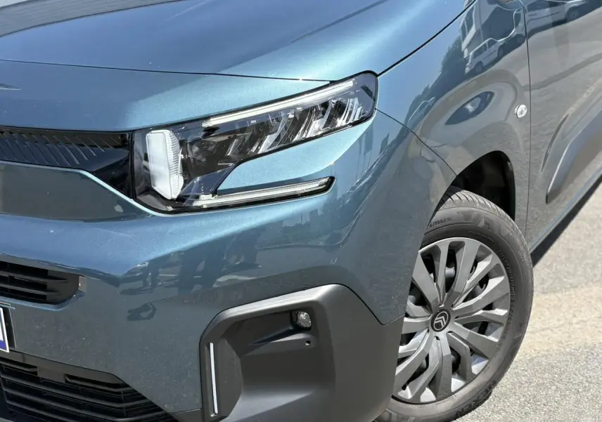 Gros plan sur l'avant droit bleu Kiama du Citroën Berlingo ë-136 avec phares LED et jante tôles 16 pouces.
