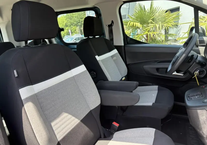 Vue intérieure côté droit du Citroën Berlingo ë-136 2025, sièges tissu noir et gris avec accoudoirs.