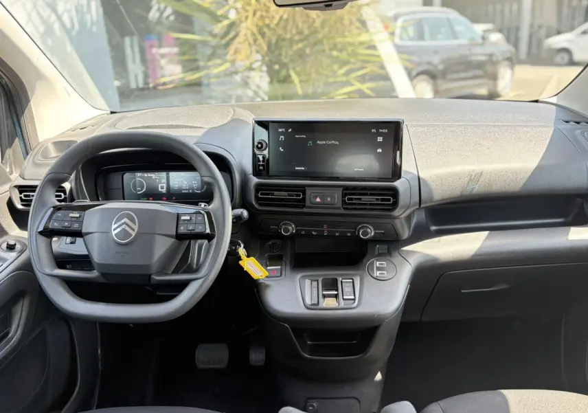 Vue intérieure avant du Citroën Berlingo ë-136 2025, tableau de bord avec écran tactile et volant multifonction noir.