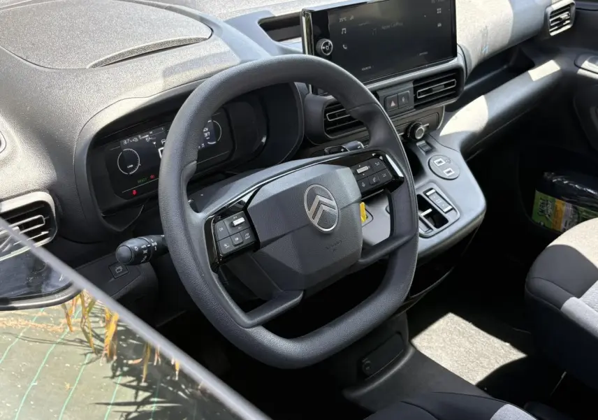 Vue intérieure du poste de conduite du Citroën Berlingo ë-136 2025, avec volant multifonction et écran tactile central.