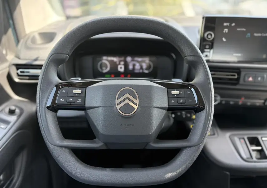Vue centrée du volant multifonction noir du Citroën Berlingo ë-136 2025 avec tableau de bord numérique et écran tactile.