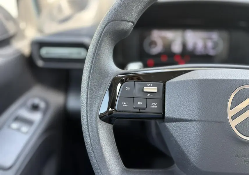 Gros plan sur le volant multifonction gris du Citroën Berlingo ë-136 2025 avec commandes intégrées côté gauche.