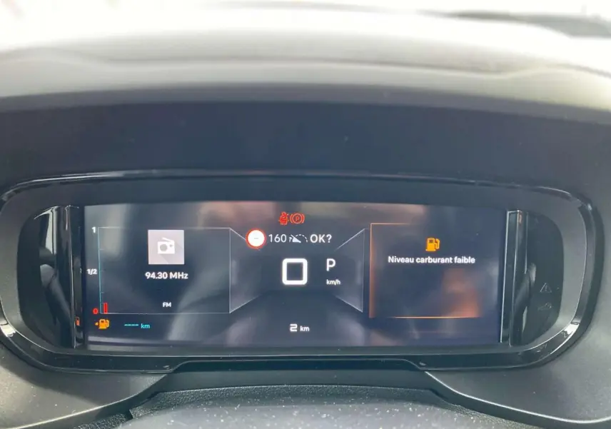 Tableau de bord numérique du Citroën Berlingo 2025 affichant la vitesse à 0 km/h et un avertissement de niveau carburant faible.