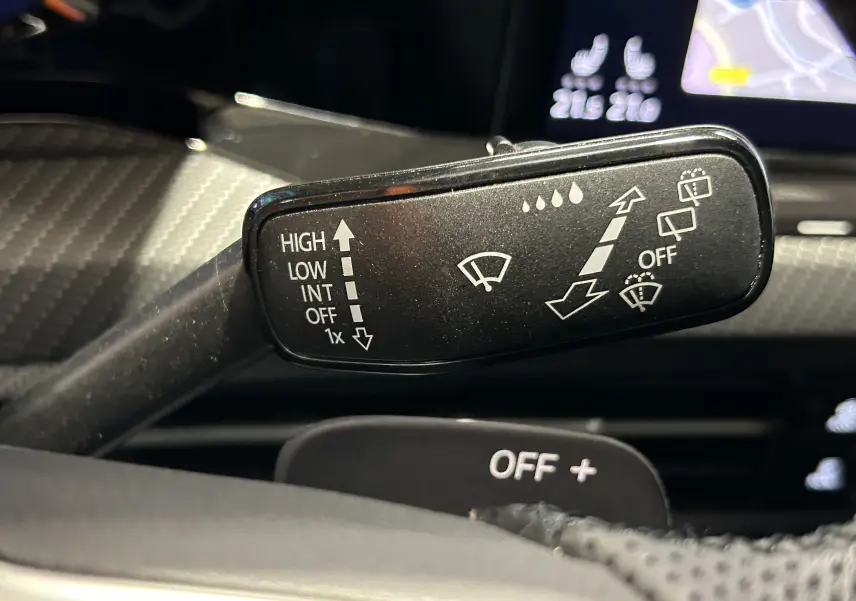 Gros plan sur la commande des essuie-glaces dans l’habitacle d’une Volkswagen Golf VIII eTSI noire, affichage digital en arrière-plan.