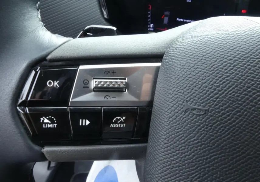 Gros plan sur les commandes de régulateur et assistant de conduite au volant cuir noir du DS4 gris métallisé 2024.
