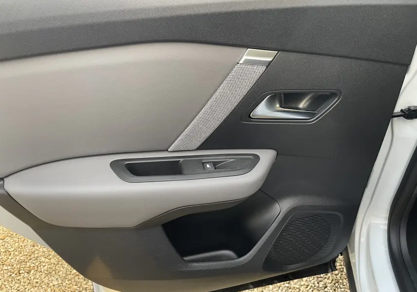 Détail de la porte avant droite de la Citroën C4 blanche, avec insert gris et poignée métallique, intérieur noir et gris.