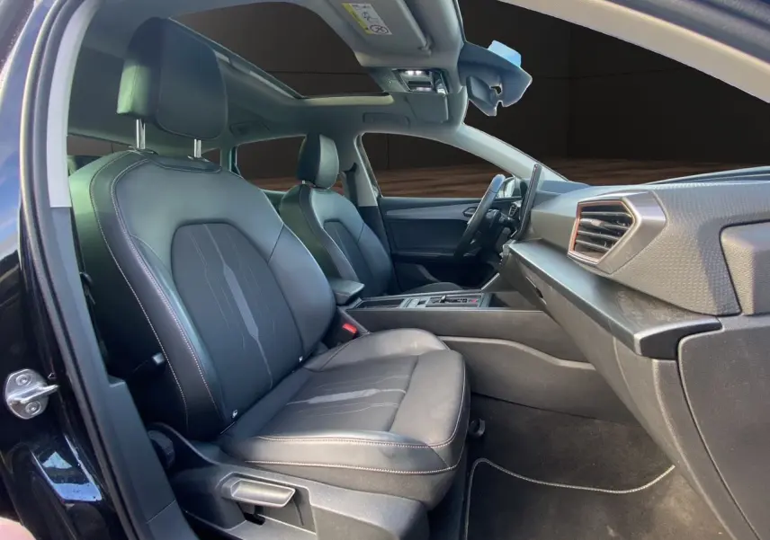 Intérieur noir de la CUPRA Leon 2023 vu côté passager, avec toit ouvrant panoramique et sièges en cuir tissu.