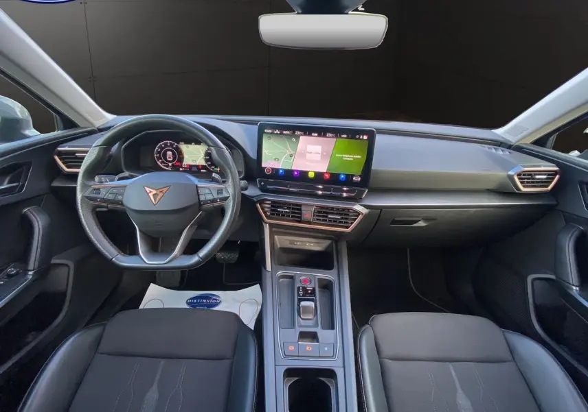 Vue intérieure frontale du tableau de bord et volant noir de la CUPRA Leon 2023 avec écran tactile central et finitions modernes.