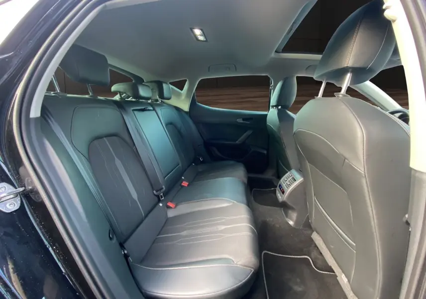 Vue intérieure arrière de la CUPRA Leon 2023 noire, montrant les sièges en cuir noir et le toit ouvrant panoramique.