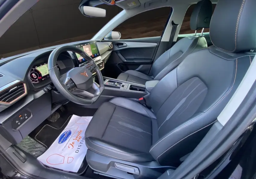 Vue intérieure côté conducteur de la CUPRA Leon 2023 noire, avec sièges cuir noir et tableau de bord digital.