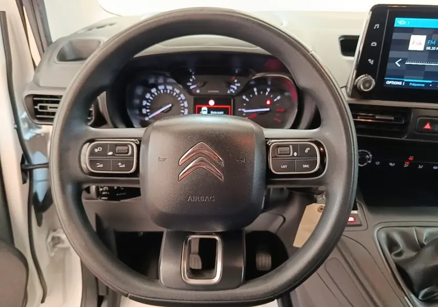 Vue intérieure centrée sur le volant multifonctions noir du Citroën Berlingo blanc avec tableau de bord et écran tactile.