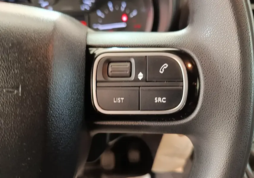 Gros plan sur les commandes multifonctions noires du volant réglable du Citroën Berlingo blanc, version 2021.