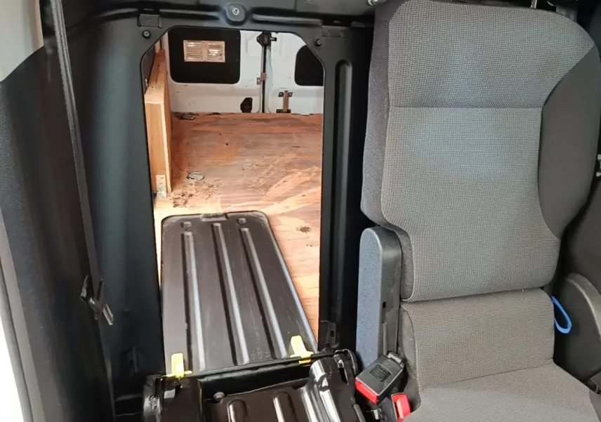 Vue intérieure du Citroën Berlingo blanc, montrant le siège passager et la cloison pleine vers l’espace de chargement en bois.