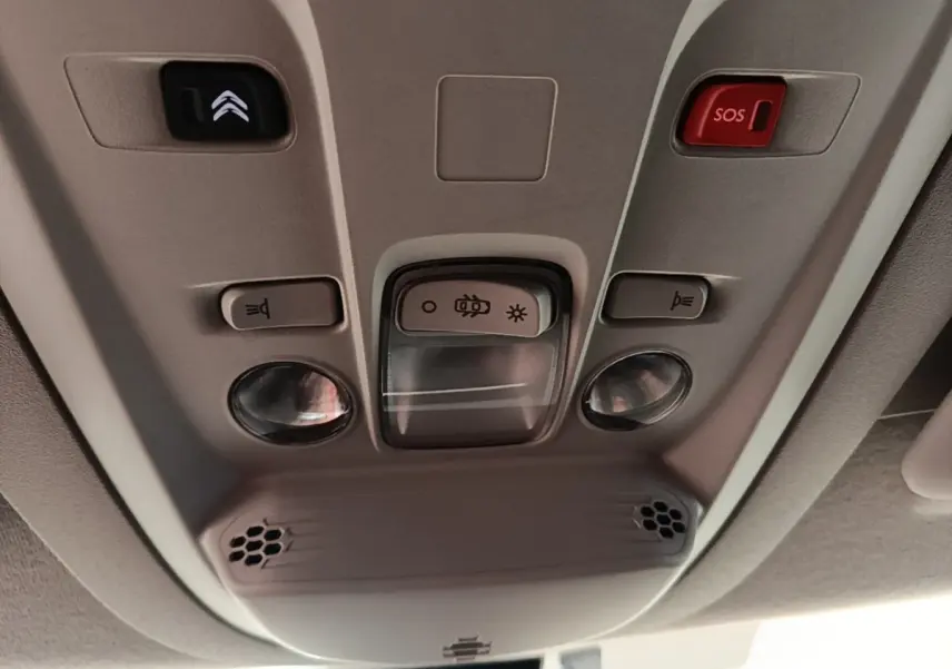 Plafonnier intérieur gris avec boutons d’éclairage, alarme SOS et commandes dans un Citroën Berlingo blanc, vue de dessous.