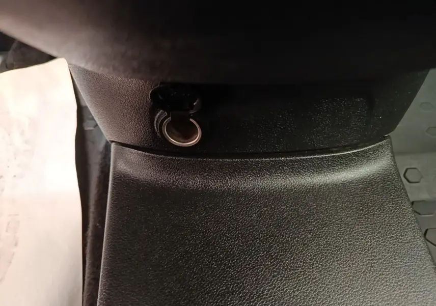 Prise 12V noire en gros plan dans l’habitacle du Citroën Berlingo blanc, vue centrée vers le bas.