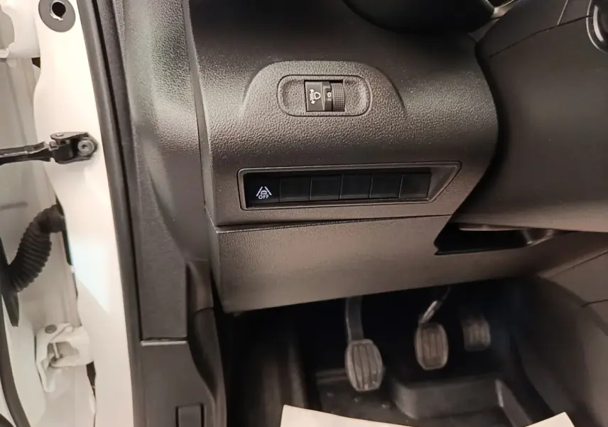 Détail intérieur côté conducteur du Citroën Berlingo blanc 2021 montrant les commandes d’éclairage et pédales manuelles.