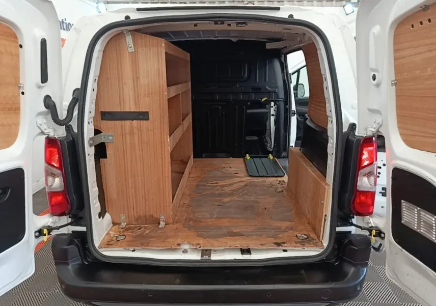 Vue arrière du Citroën Berlingo blanc 2021 avec portes ouvertes, aménagement bois intérieur et cloison pleine noire.