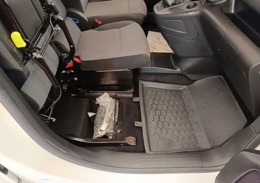 Vue intérieure côté passager avant du Citroën Berlingo blanc, siège relevé et tapis de sol caoutchouc visible.