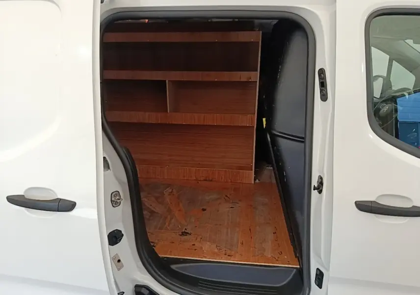 Vue latérale gauche d’un Citroën Berlingo blanc avec porte coulissante ouverte montrant l’aménagement intérieur en bois.