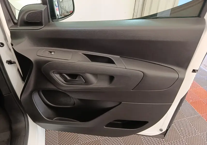 Vue rapprochée de la porte avant gauche noire du Citroën Berlingo blanc, avec poignée et commande de vitre.