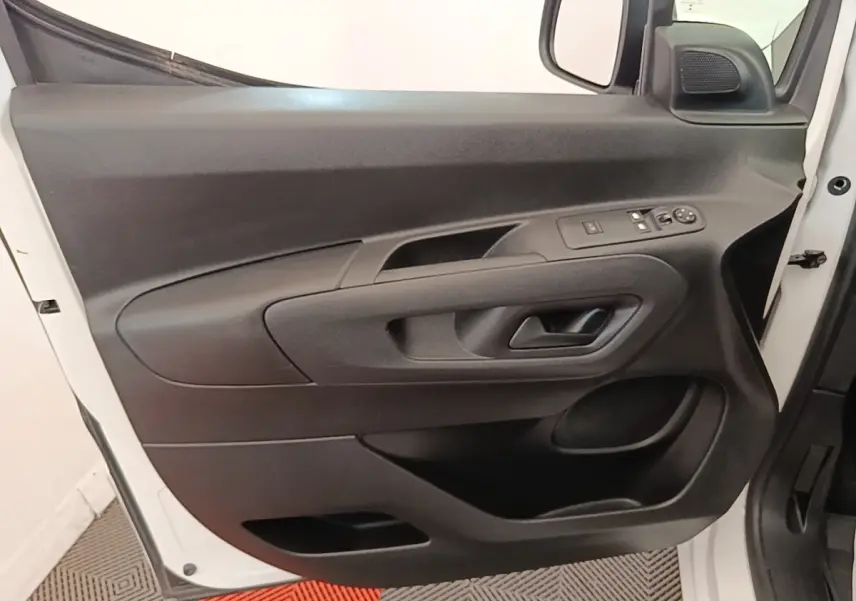 Porte avant gauche ouverte d’un Citroën Berlingo blanc, montrant les commandes électriques et la poignée intérieure noire.