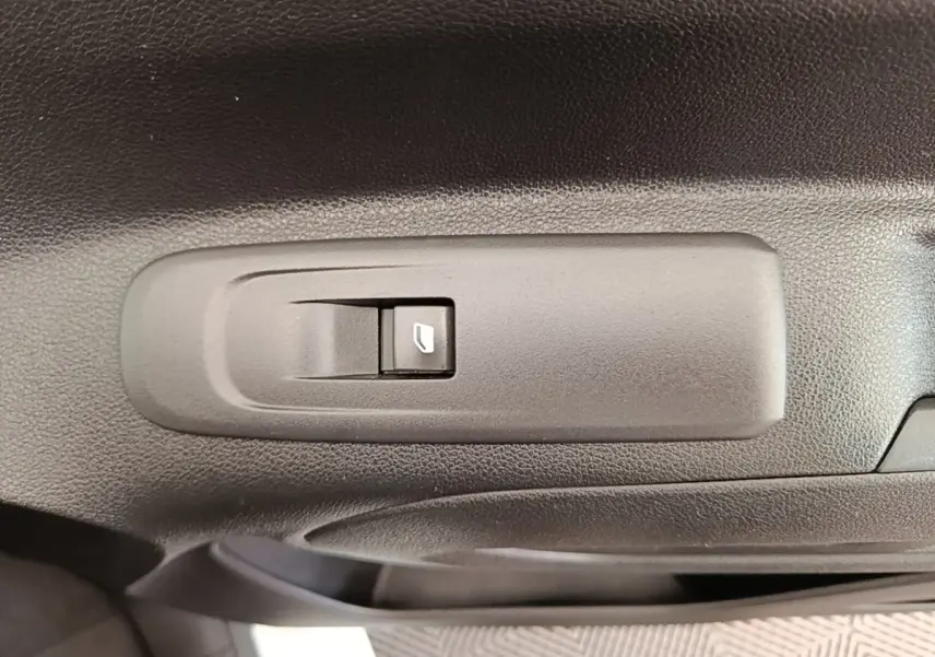 Gros plan sur le bouton de commande de la vitre électrique côté conducteur dans une Citroën Berlingo blanc, version 2021.