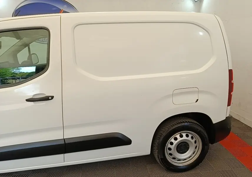 Vue de profil côté droit d’un utilitaire Citroën Berlingo blanc avec porte latérale pleine et jante acier.