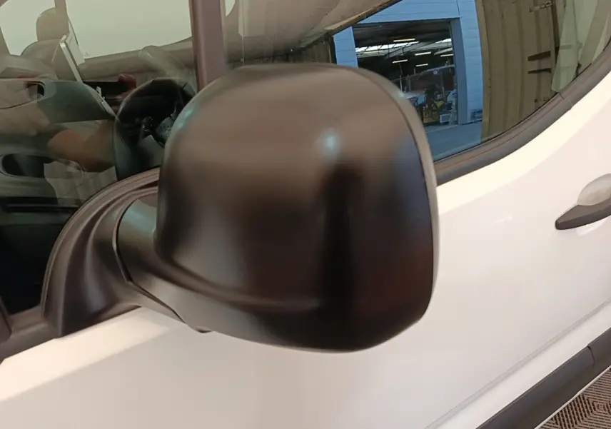 Gros plan sur le rétroviseur droit noir du Citroën Berlingo blanc, vue latérale avant du véhicule.