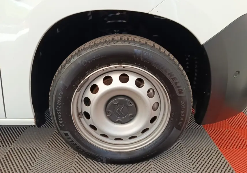 Gros plan sur la roue avant droite d’un Citroën Berlingo blanc avec jante acier et pneu Michelin.