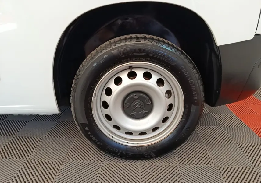 Gros plan sur la roue avant droite acier d’un Citroën Berlingo blanc, avec logo Citroën au centre de la jante.