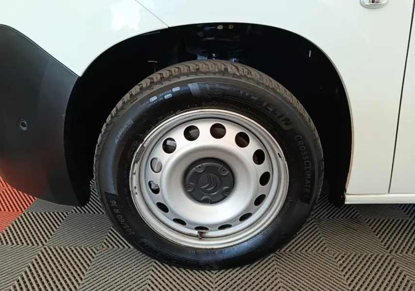 Gros plan sur la roue avant droite acier d’un Citroën Berlingo blanc, avec pneu Michelin CrossClimate visible.