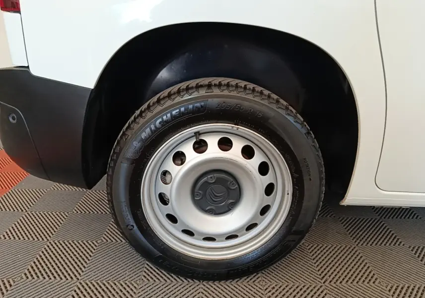 Gros plan sur la roue arrière droite d’un Citroën Berlingo blanc avec jante acier et pneu Michelin.
