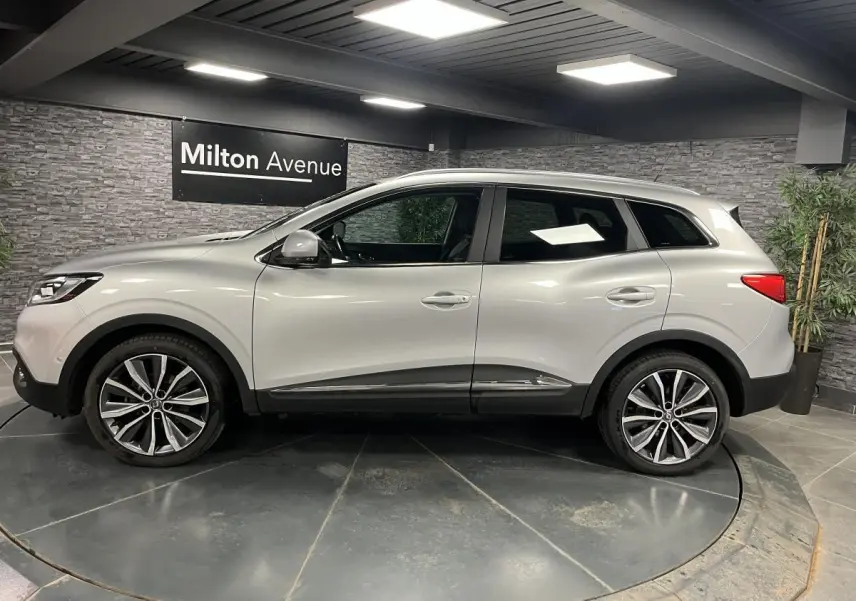 Renault Kadjar gris platine vu de profil côté gauche, avec jantes alliage 19 pouces et attelage fixe visible.