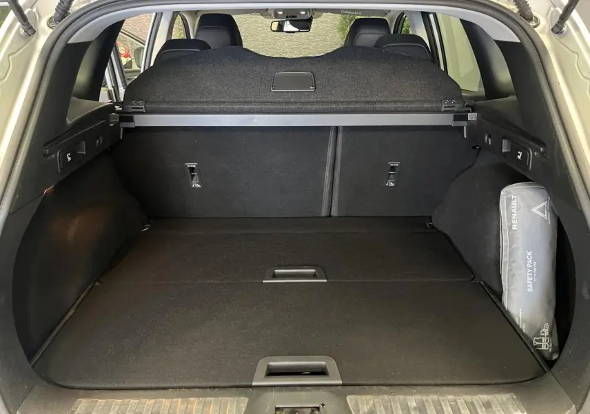 Coffre ouvert d'un Renault Kadjar gris, vue arrière montrant la tablette cache-bagages et un kit de sécurité Renault.