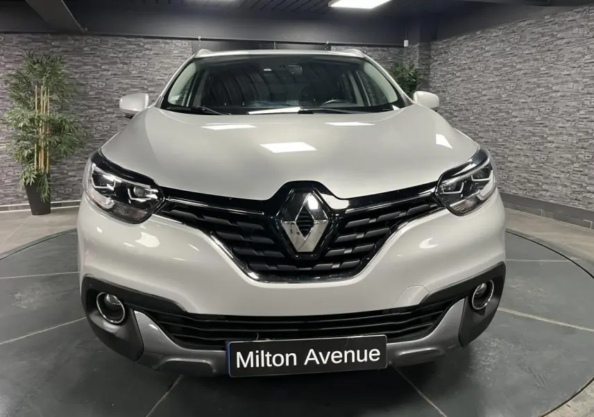 Vue de face d'un Renault Kadjar gris platine avec calandre noire et projecteurs Full LED dans un showroom.