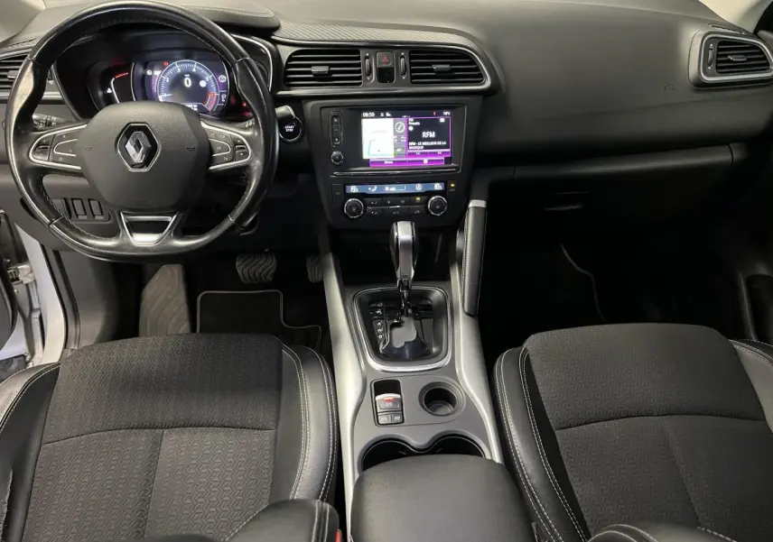 Vue intérieure avant du Renault Kadjar 2017 avec tableau de bord noir et console centrale intégrant levier de boîte auto.
