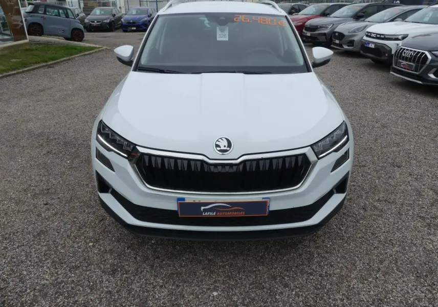 Vue avant d'un SUV Skoda Karoq blanc 2024 avec calandre noire et phares LED, en extérieur sur parking.