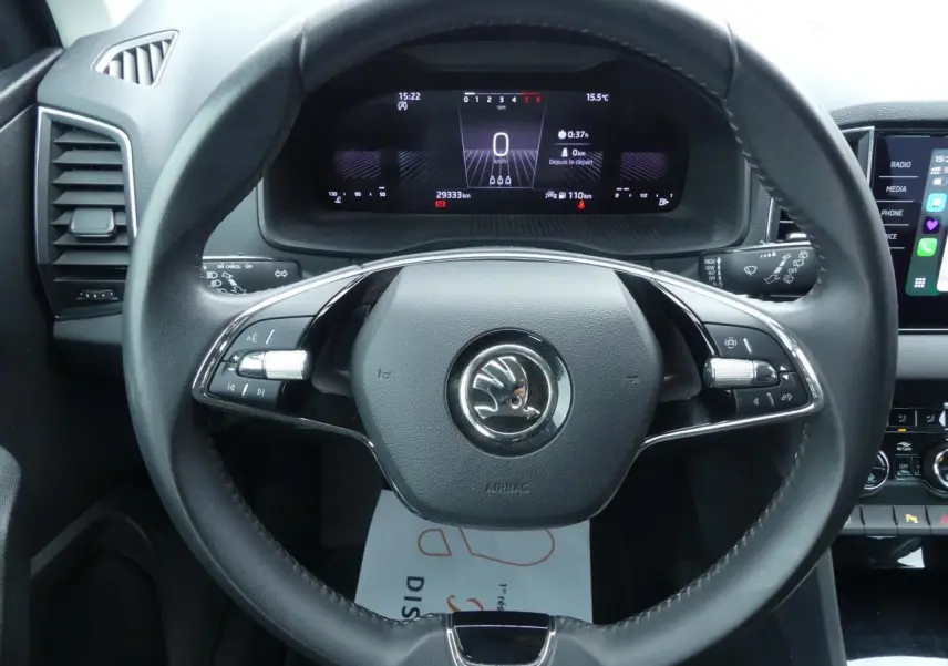 Vue frontale du volant cuir noir multifonctions et du tableau de bord digital du Skoda Karoq blanc 2024.