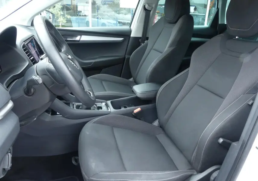 Intérieur avant côté conducteur du Skoda Karoq blanc 2024, sièges tissu noir et console centrale avec accoudoir