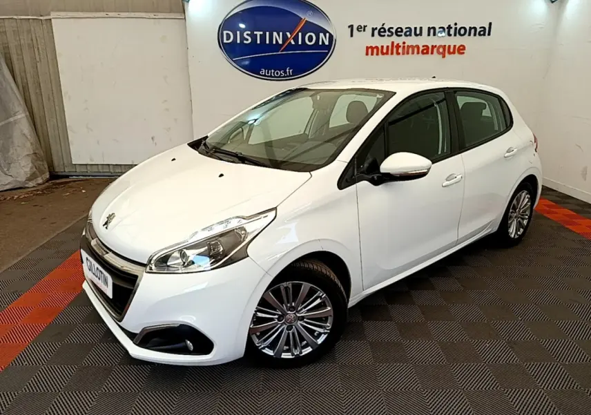 Peugeot 208 Puretech 82 Signature blanc vue 3/4 avant droit dans un showroom avec sol gris et rouge.