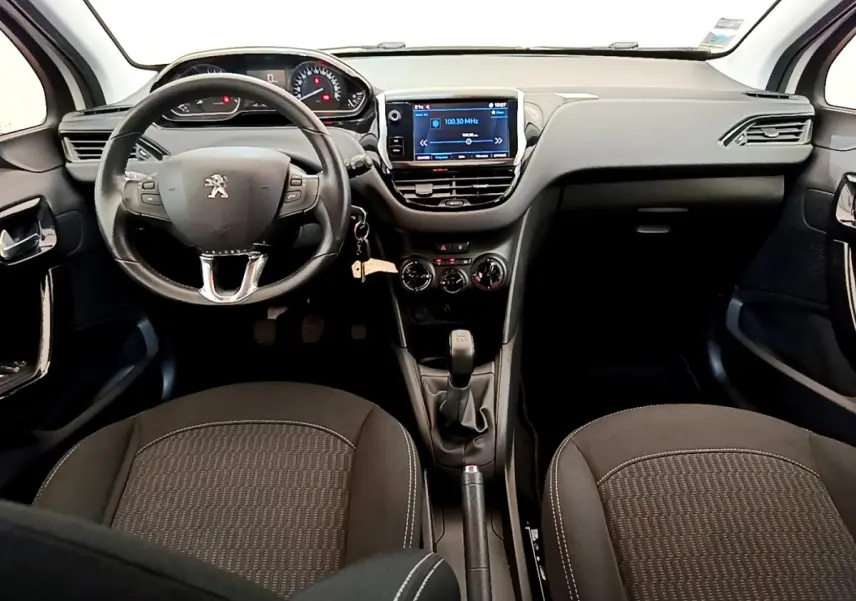 Vue intérieure avant du Peugeot 208 blanc 2019, volant cuir multifonctions et écran tactile central visible.