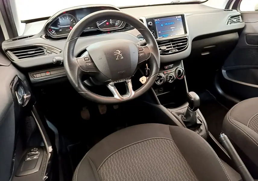 Intérieur noir de la Peugeot 208 Puretech 82 Signature 2019, vue du poste de conduite avec volant cuir et écran tactile central.