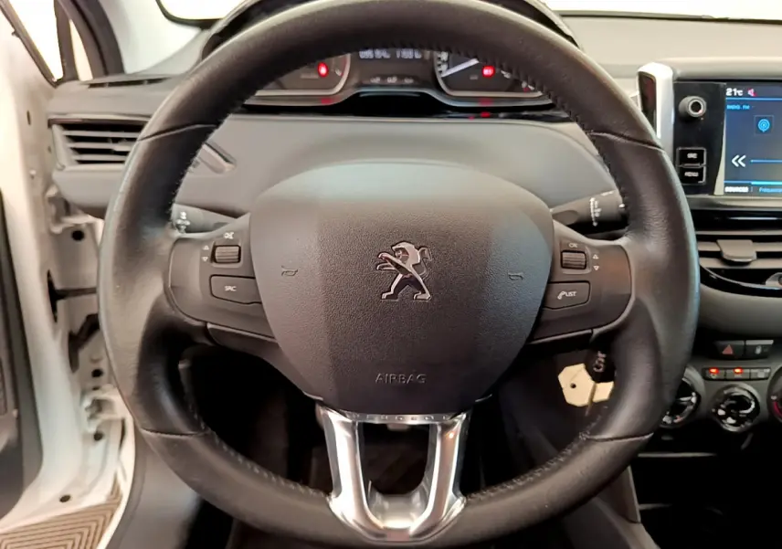 Vue rapprochée du volant cuir noir de la Peugeot 208 Puretech 82 Signature 2019 avec tableau de bord et écran tactile.
