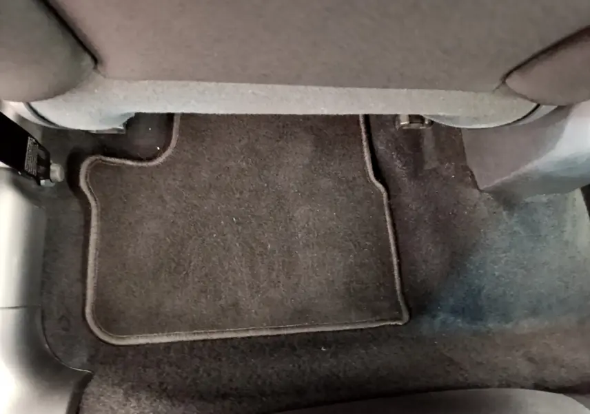 Vue rapprochée du tapis de sol noir sous le siège avant droit d'une Peugeot 208 Puretech 82 Signature blanche de 2019.