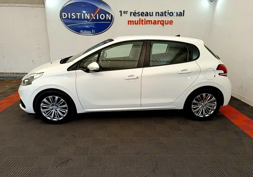 Profil latéral droit d'une Peugeot 208 blanche Puretech 82 Signature de 2019 dans un showroom multimarque.