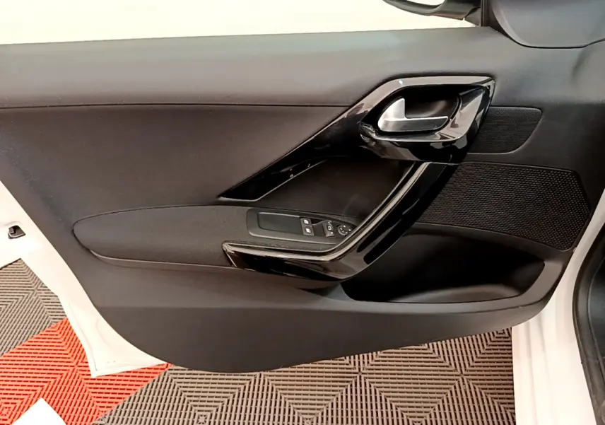 Intérieur de la porte avant gauche noire de la Peugeot 208 Puretech 82 Signature blanche, avec poignée et commandes électriques.