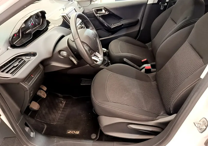 Intérieur avant droit de la Peugeot 208 Puretech 82 Signature 2019 avec sièges noirs et tableau de bord moderne.