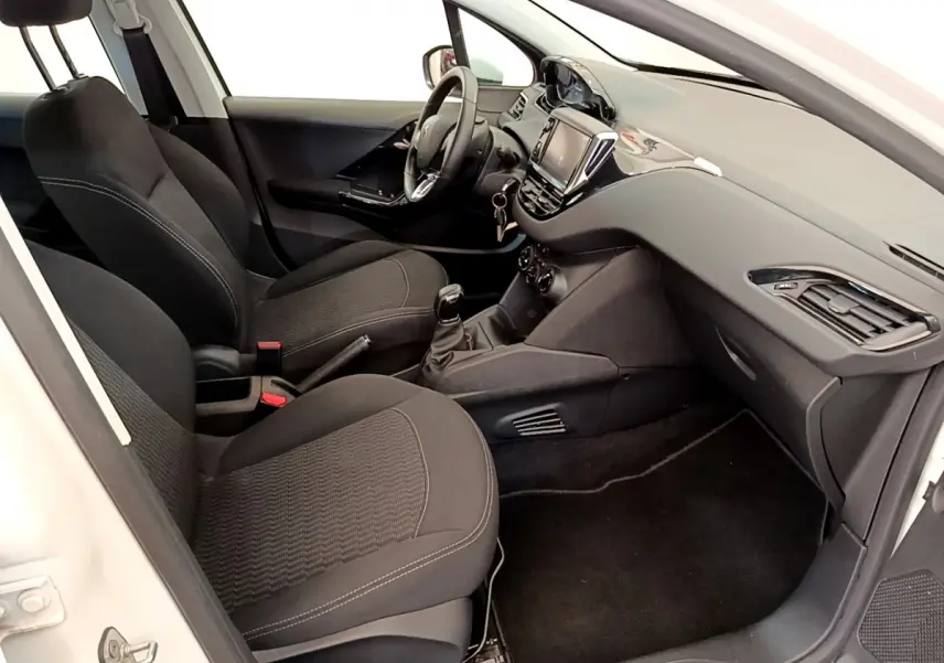 Intérieur de la Peugeot 208 blanc vue côté passager, sièges noirs et tableau de bord avec écran tactile.