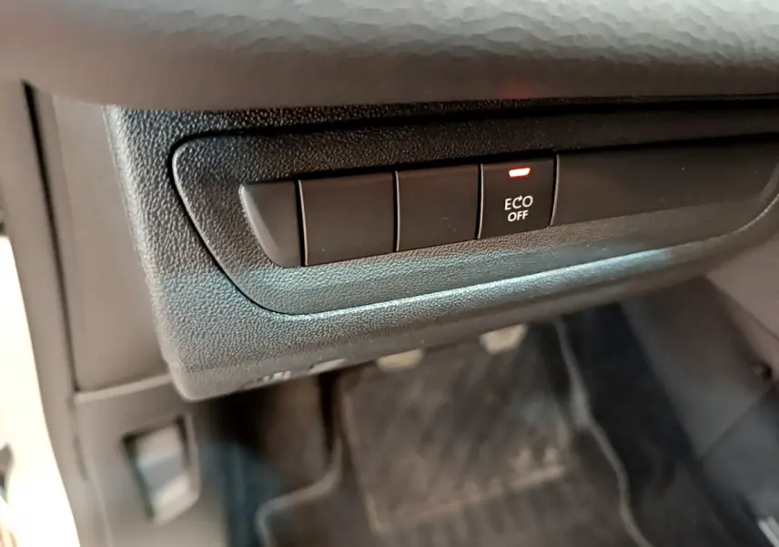 Gros plan sur le bouton ECO OFF dans l'habitacle noir d'une Peugeot 208 Puretech 82 Signature blanche de 2019.