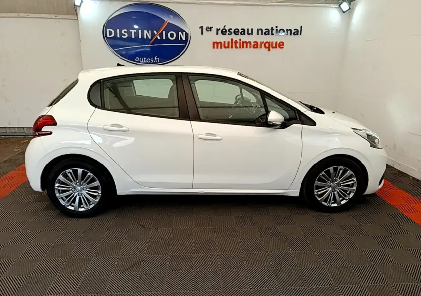 Profil latéral droit d'une Peugeot 208 Puretech 82 Signature blanche, avec jantes alliage et rétroviseurs chromés électriques.